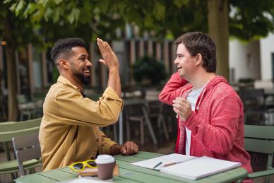 A male learner with LDD high fives his tutor