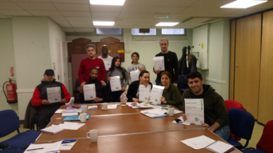 ESOL learners sitting around a table with their certificates for class completion