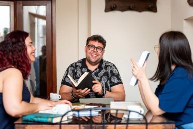A group of adults sitting around a table reading and smiling