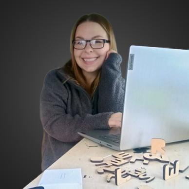 A photograph of Dr. Abbie Cairns at her desk with her laptop.