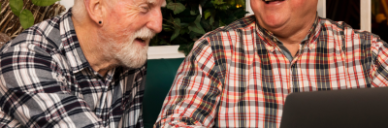 Health and Wellbeing - two males sit at a table around a laptop